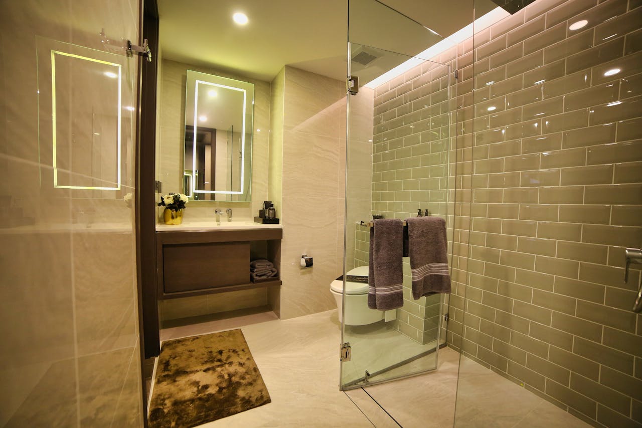 Spacious luxury bathroom featuring glass shower, illuminated mirrors, and sleek interior design.